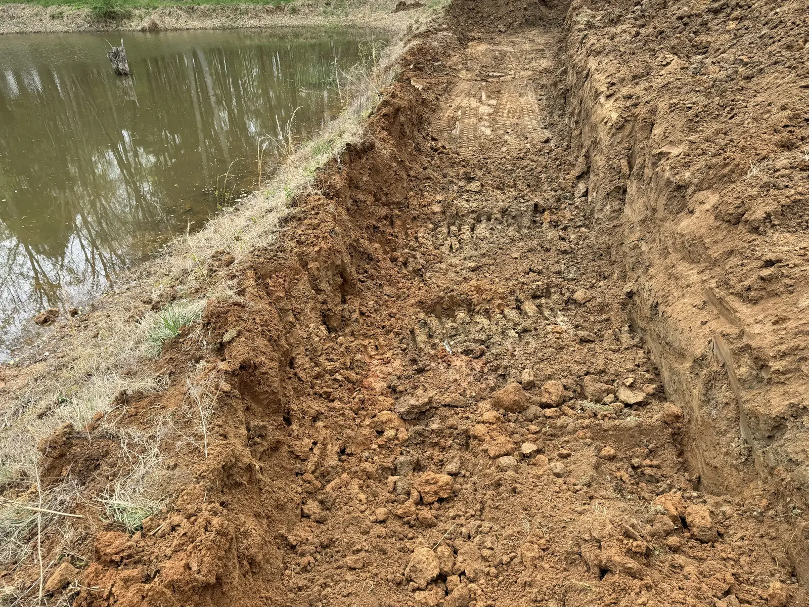 Key trench cut along the length of a pond dam, the pond at the left